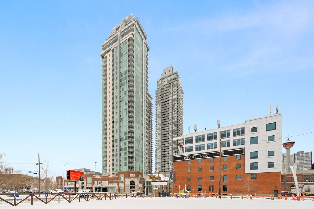 A cityscape with a large building in the middle and a smaller one to the right.