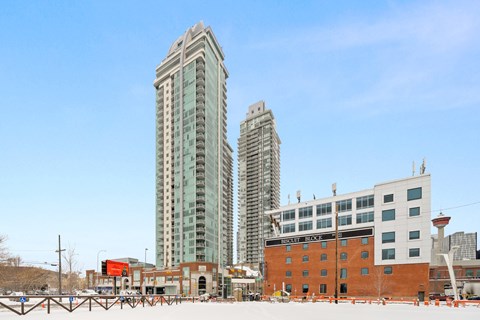 A cityscape with a large building in the middle and a smaller one to the right.