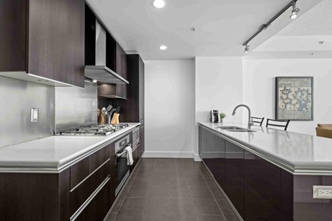 A modern kitchen with dark wood cabinets and a stainless steel stove top.