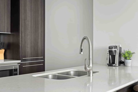 A modern kitchen with a stainless steel sink and faucet.