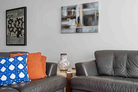 Two grey couches with pillows and a vase on a table.