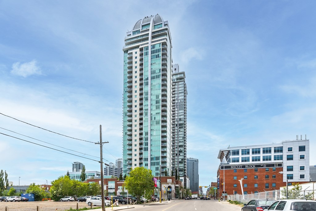 A tall glass building stands in the middle of a parking lot.