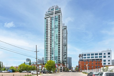 A tall glass building stands in the middle of a parking lot.