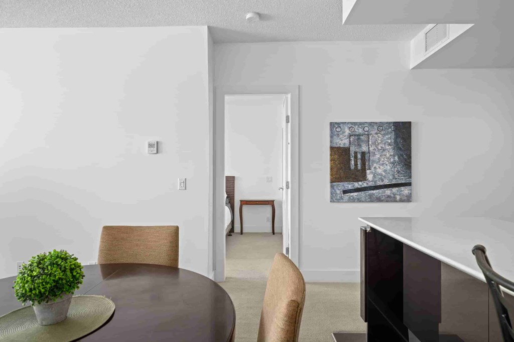 A room with a table, chairs and a painting on the wall.