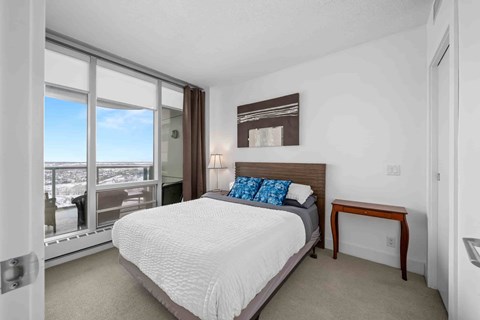 A bedroom with a large bed and a view of the city.