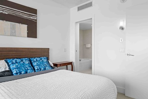 A bed with a white comforter and two blue patterned pillows.