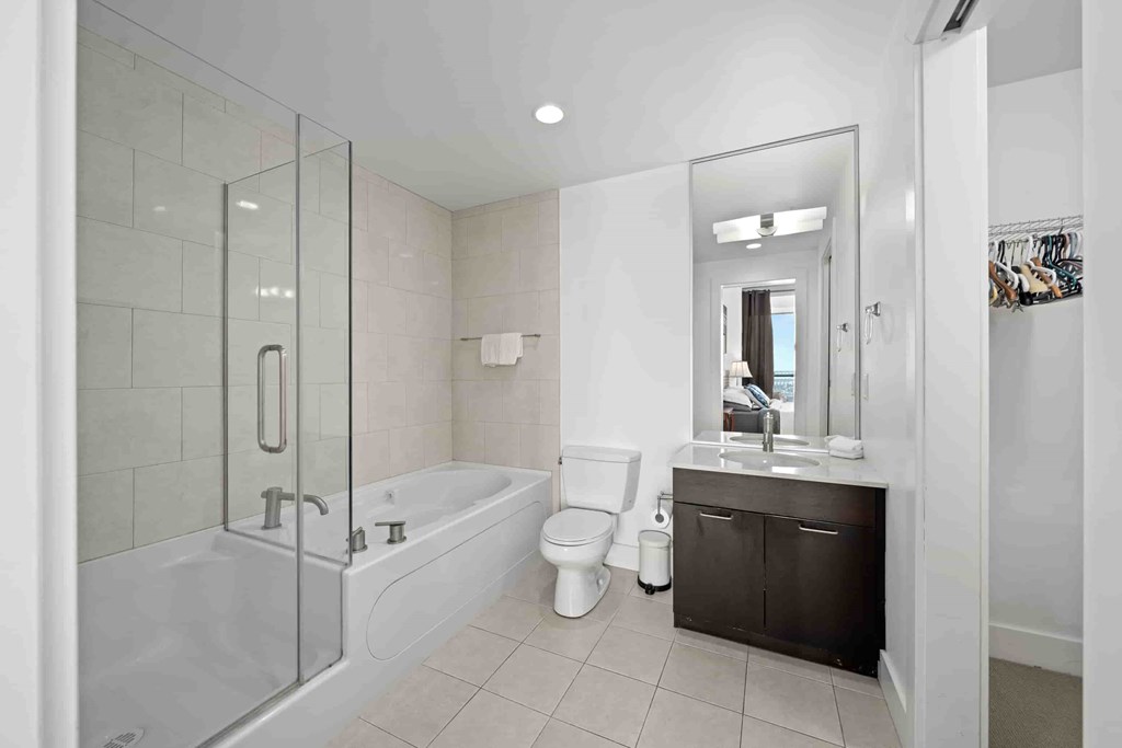 A white bathroom with a glass shower door and a white bathtub.