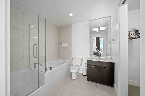 A white bathroom with a glass shower door and a white bathtub.