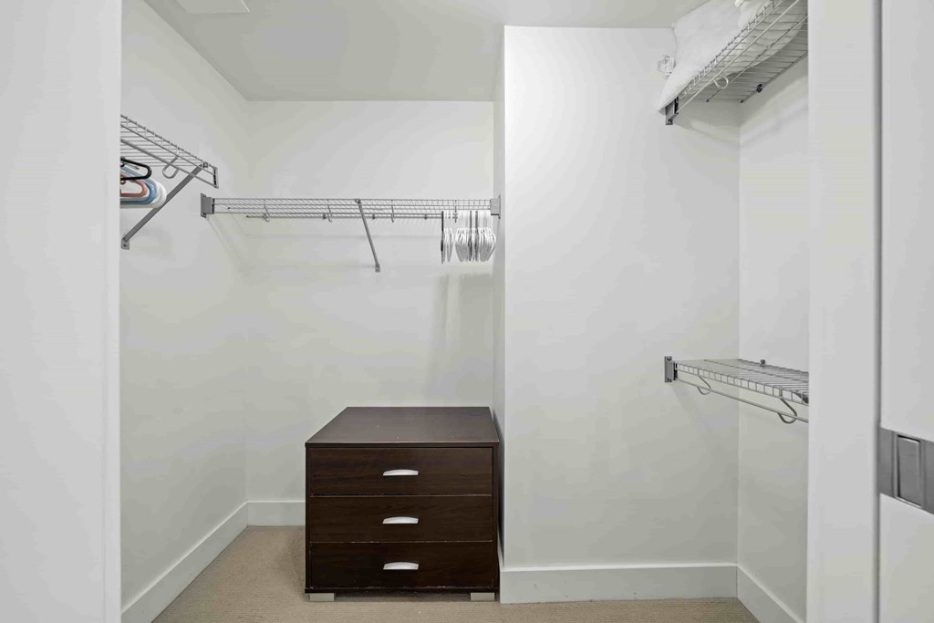 A white closet with a brown desk and drawers.