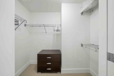 A white closet with a brown desk and drawers.