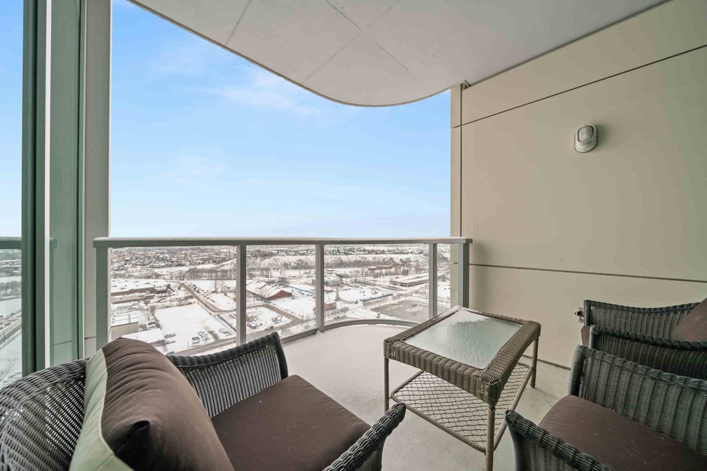 A balcony with a table and two chairs overlooking a snowy landscape.