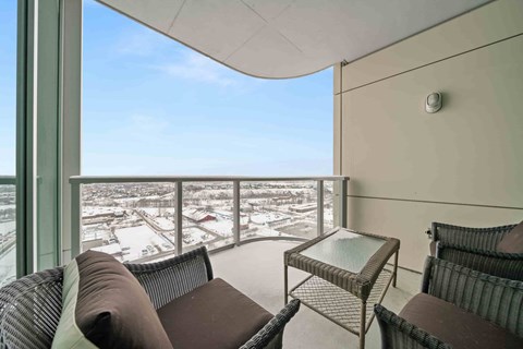 A balcony with a table and two chairs overlooking a snowy landscape.