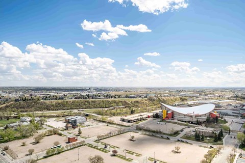 A large building with a red and white exterior is surrounded by a parking lot and other buildings.