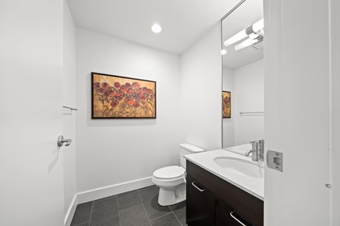 A bathroom with a toilet, sink and a painting on the wall.
