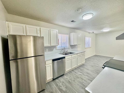 A kitchen with a stainless steel refrigerator and white cabinets.