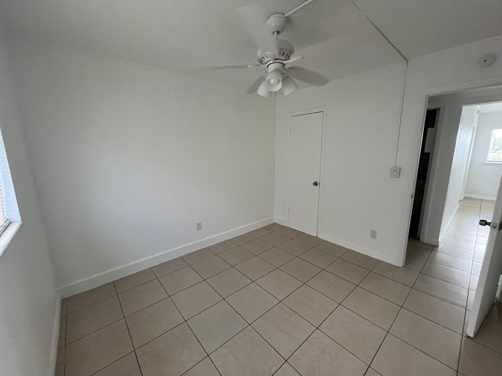 A room with a ceiling fan and tile flooring.