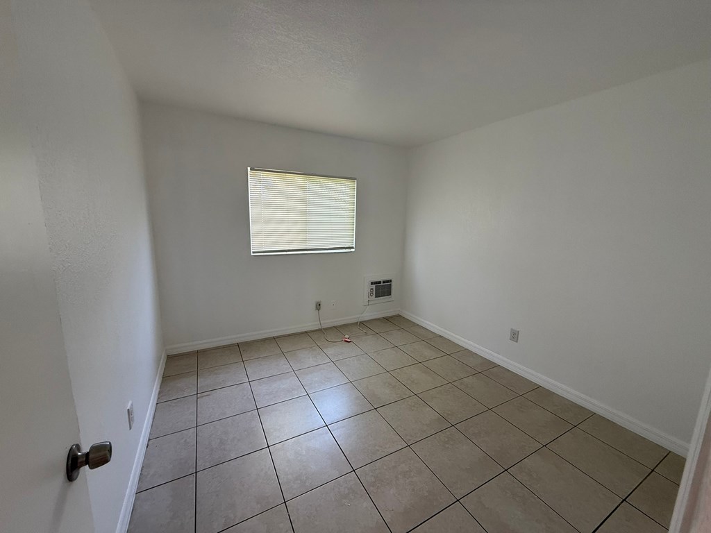 A room with white walls and a window with blinds.
