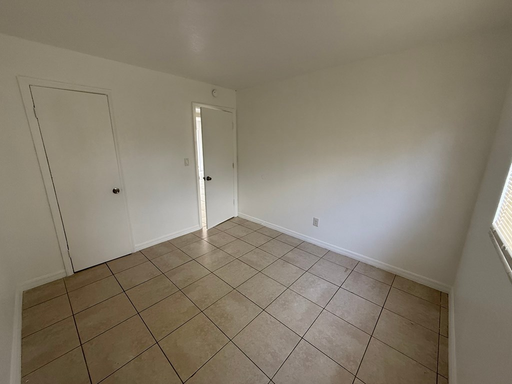 A room with tile flooring and two doors.