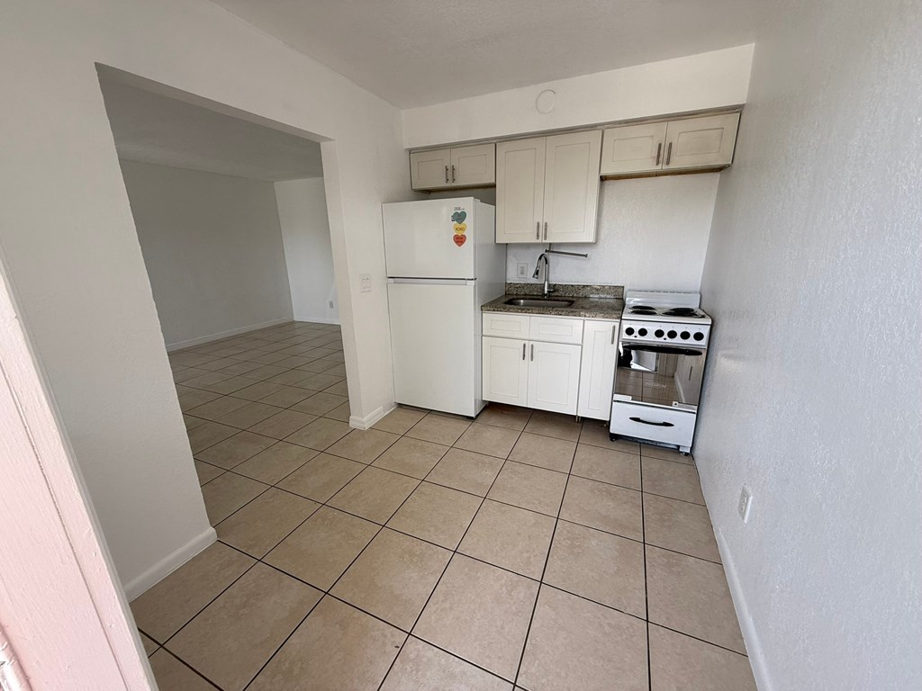 A kitchen with white appliances and beige tiles.
