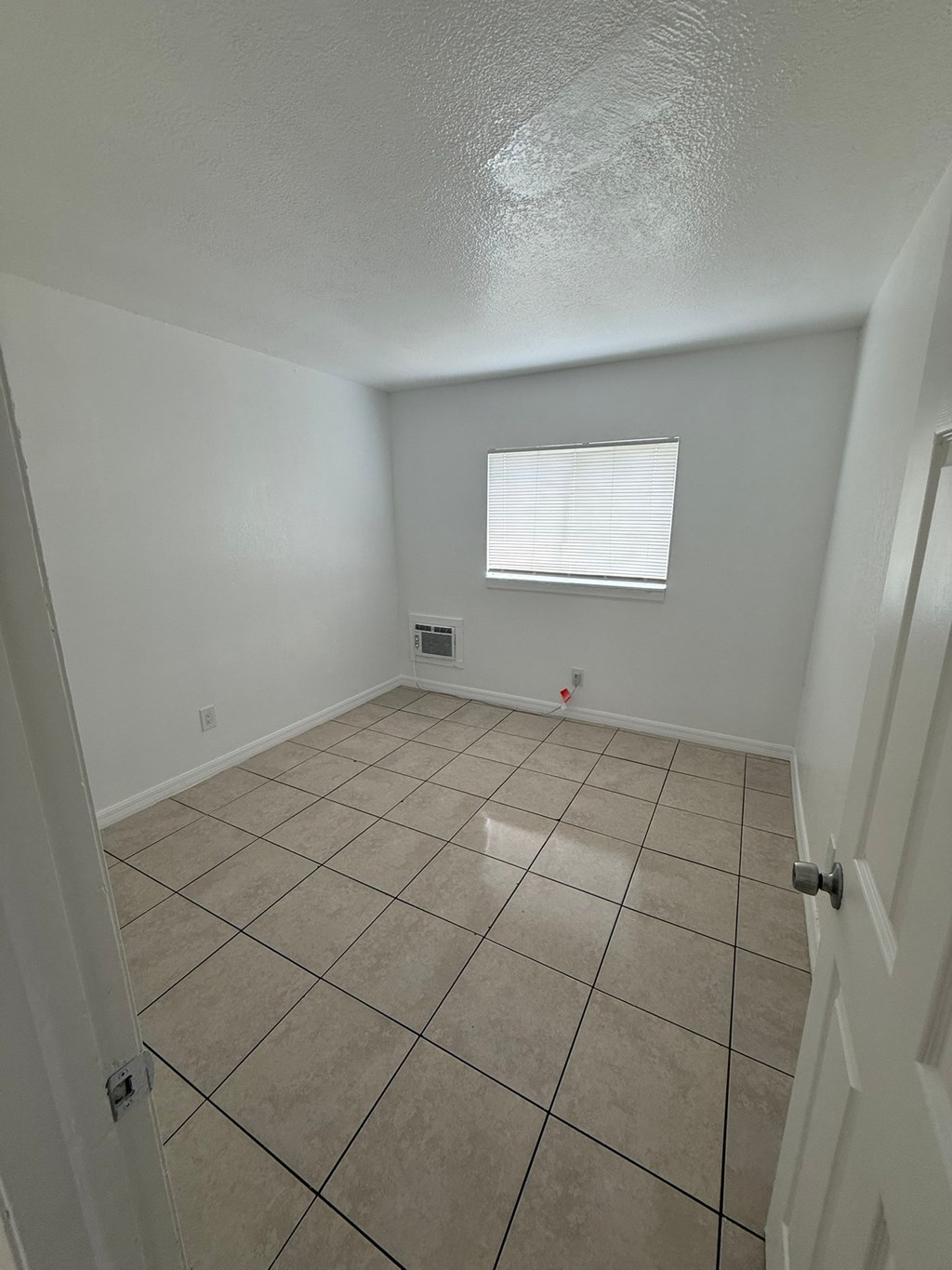 A room with a tiled floor and a window with blinds.