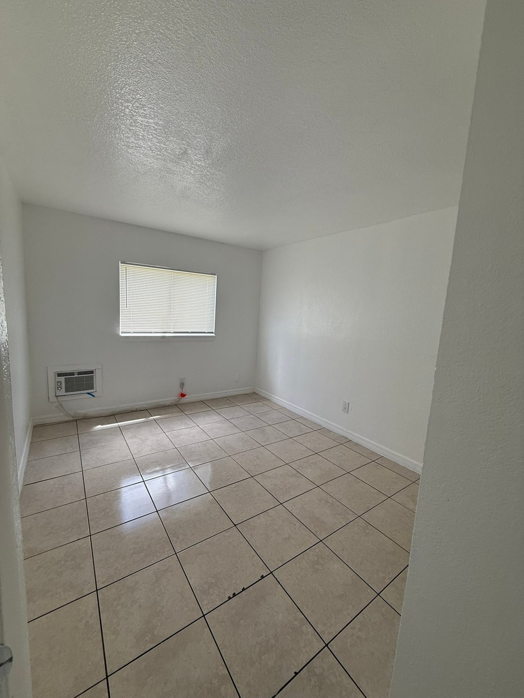 A room with a window and tiled floor.