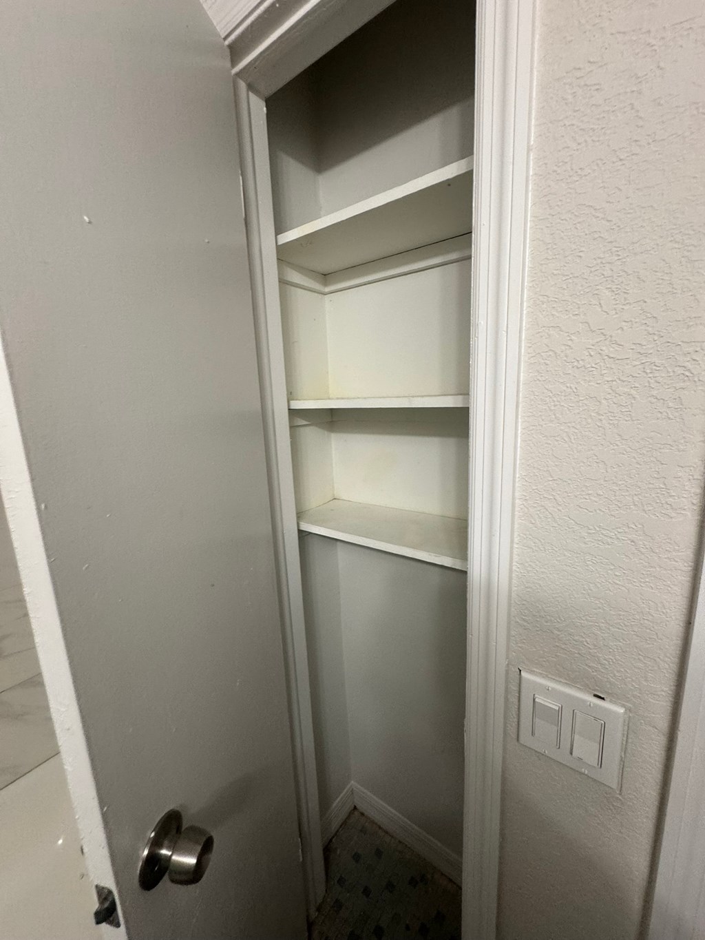 A white door with a silver handle is open to a white interior.