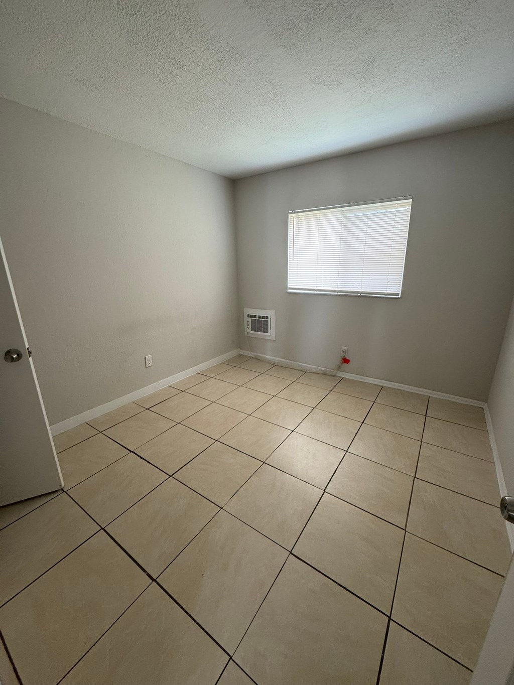 A room with a tiled floor and a window with blinds.