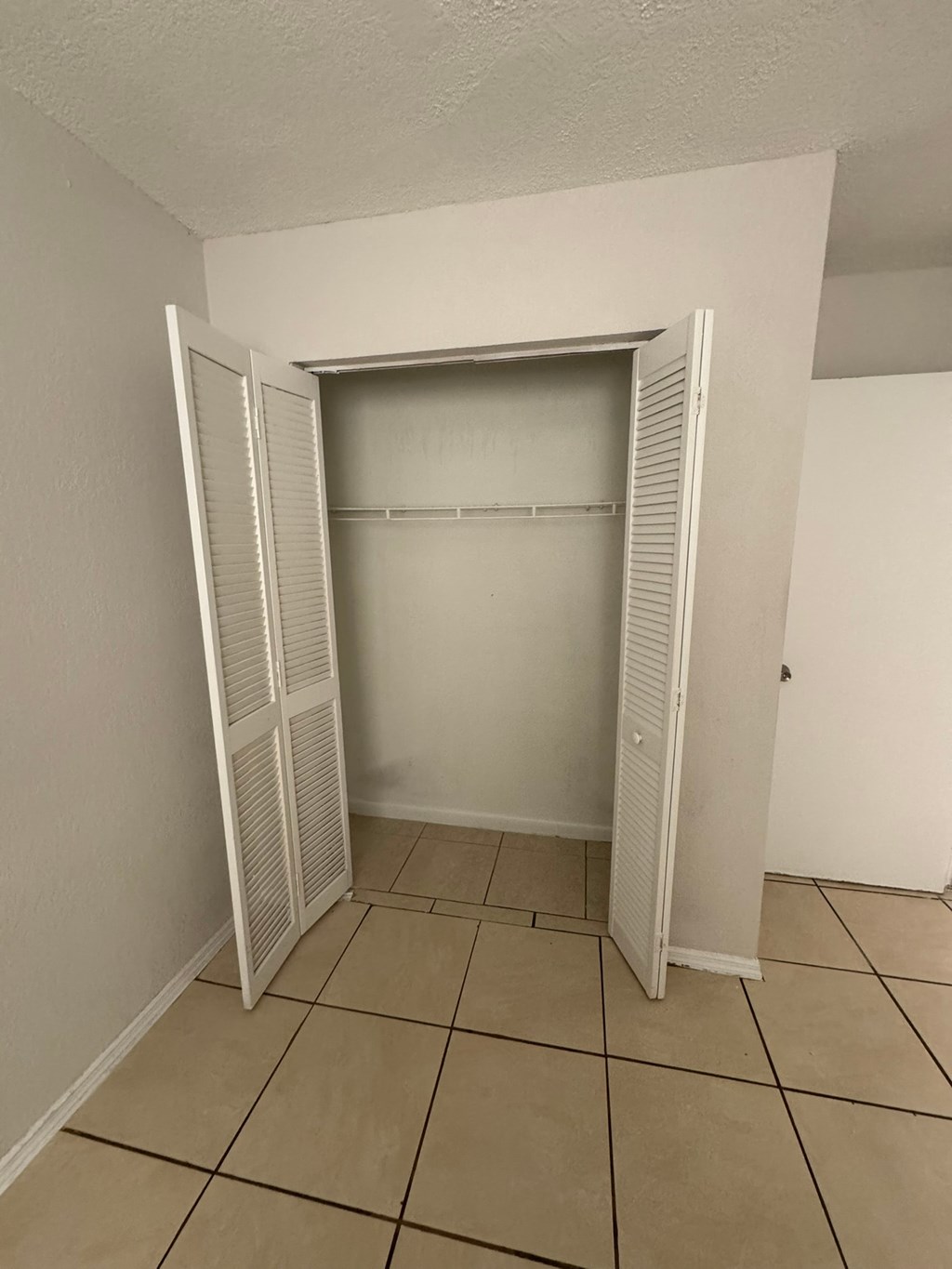 A white closet with a door open and shelves inside.