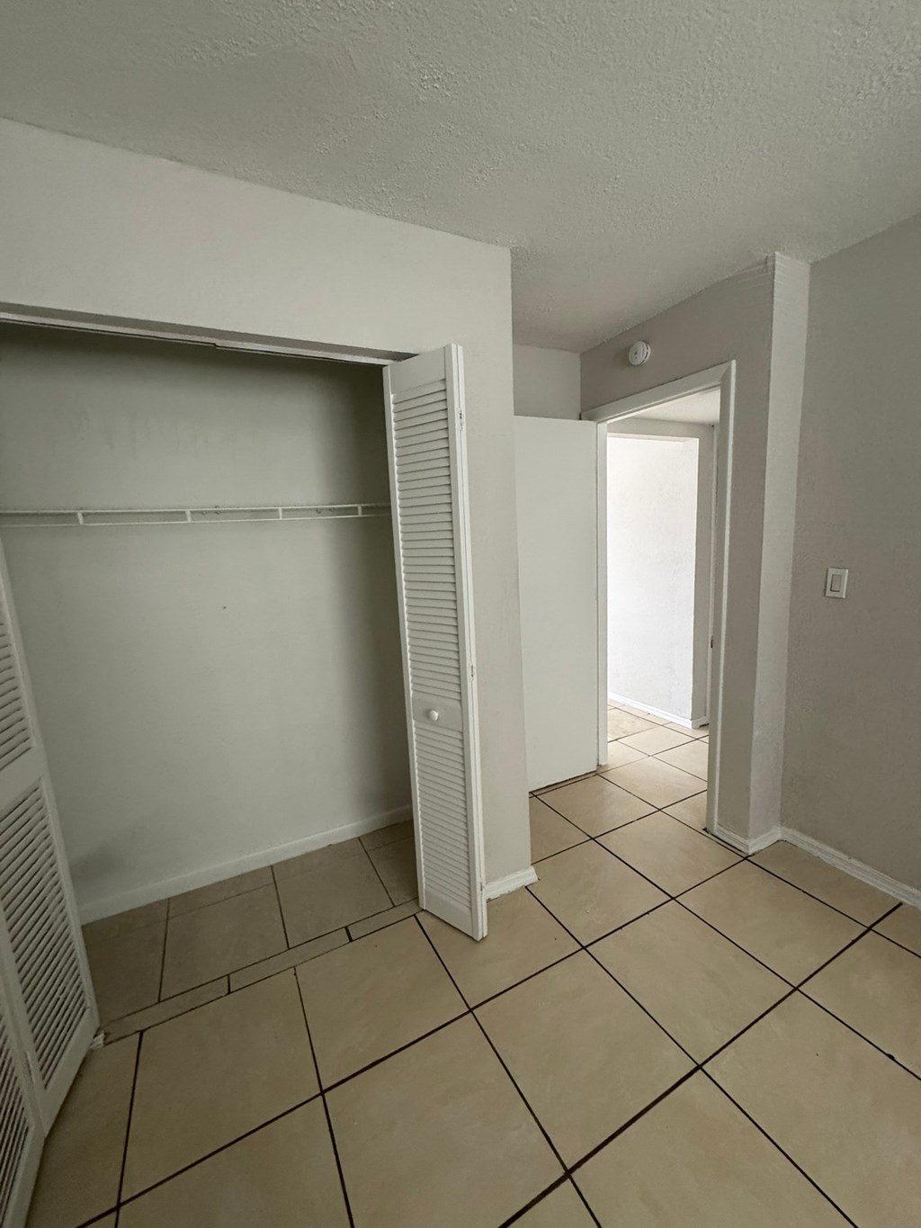 A room with a white wall and a white closet with shelves.