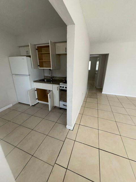 A kitchen with a white refrigerator and a stove with an open door.