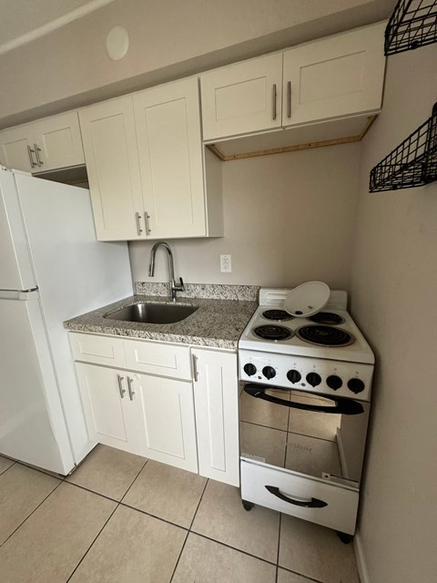A white kitchen with a stove and sink.
