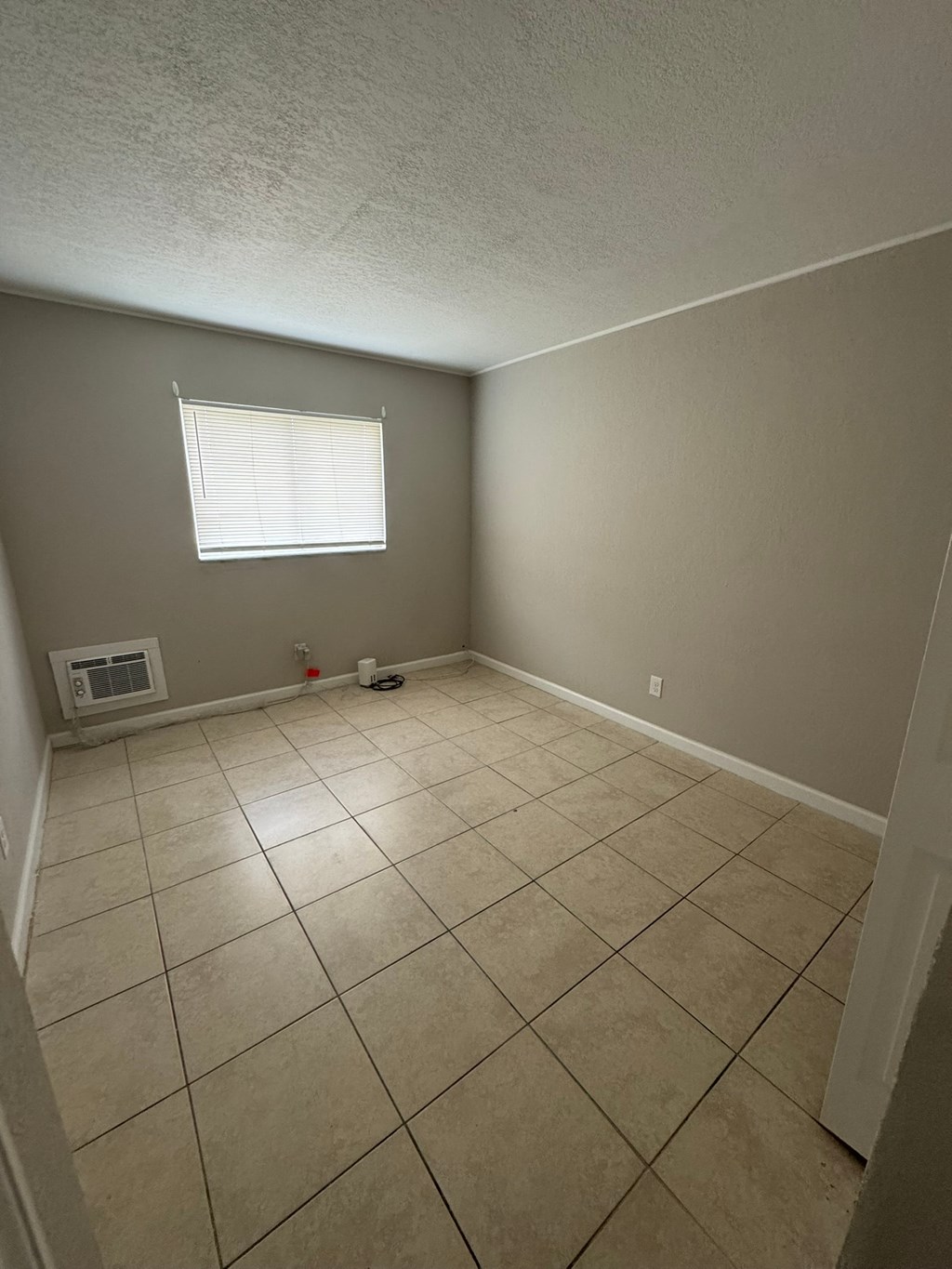 A room with a window and tiled floor.