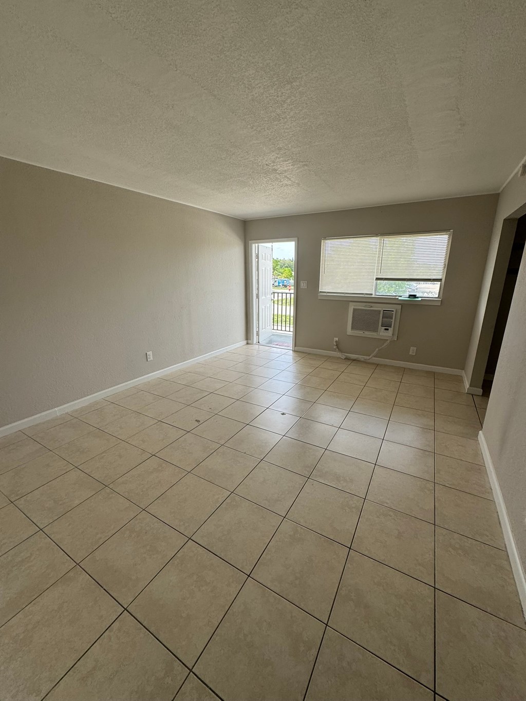 A room with beige tiled flooring and a window with blinds.