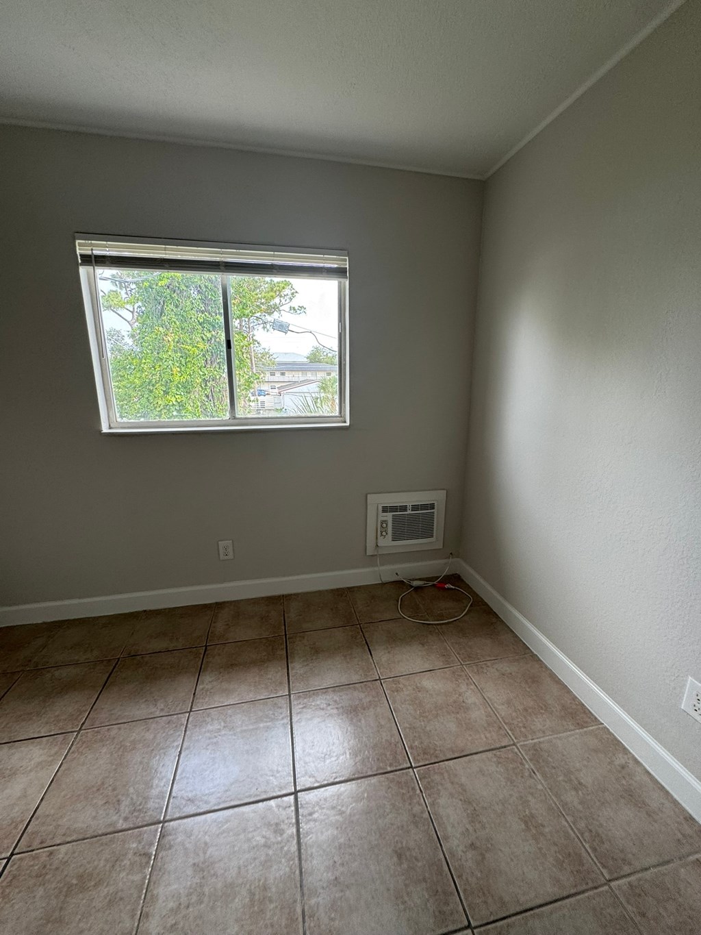 A room with a window and tiled floor.