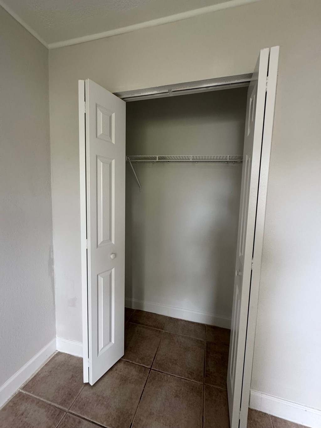 A white door is open to a closet with a shelf.