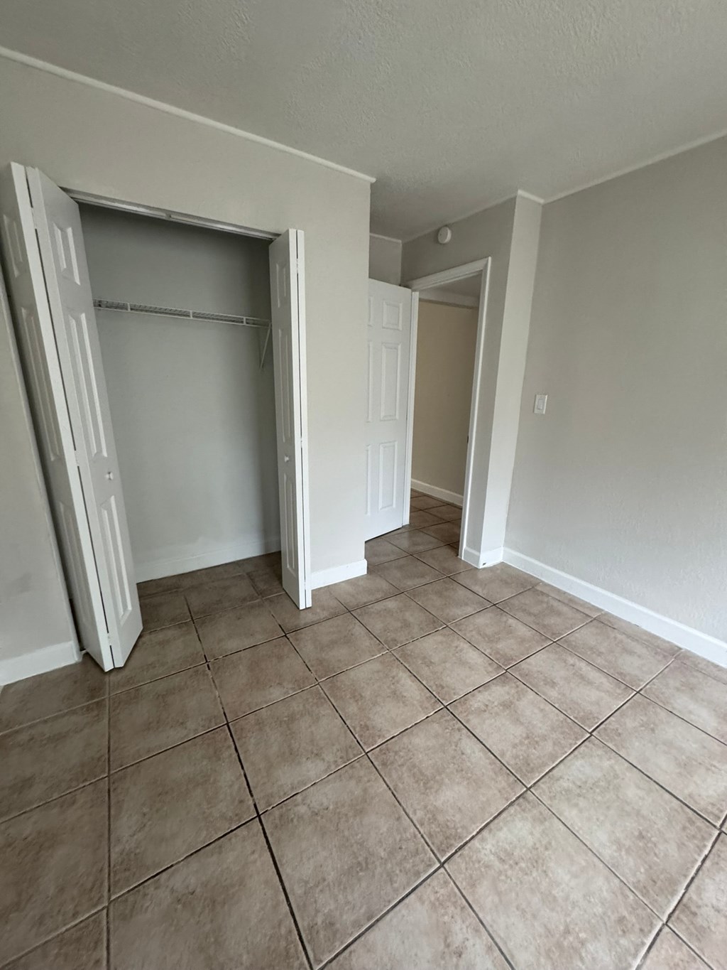 A room with a white door and a white closet with a white shelf.