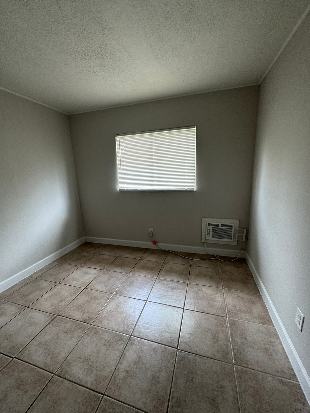 A room with a window and a tiled floor.