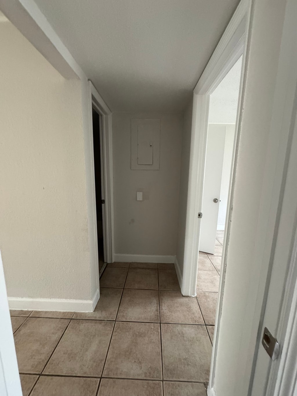 A hallway with a tiled floor and white walls.