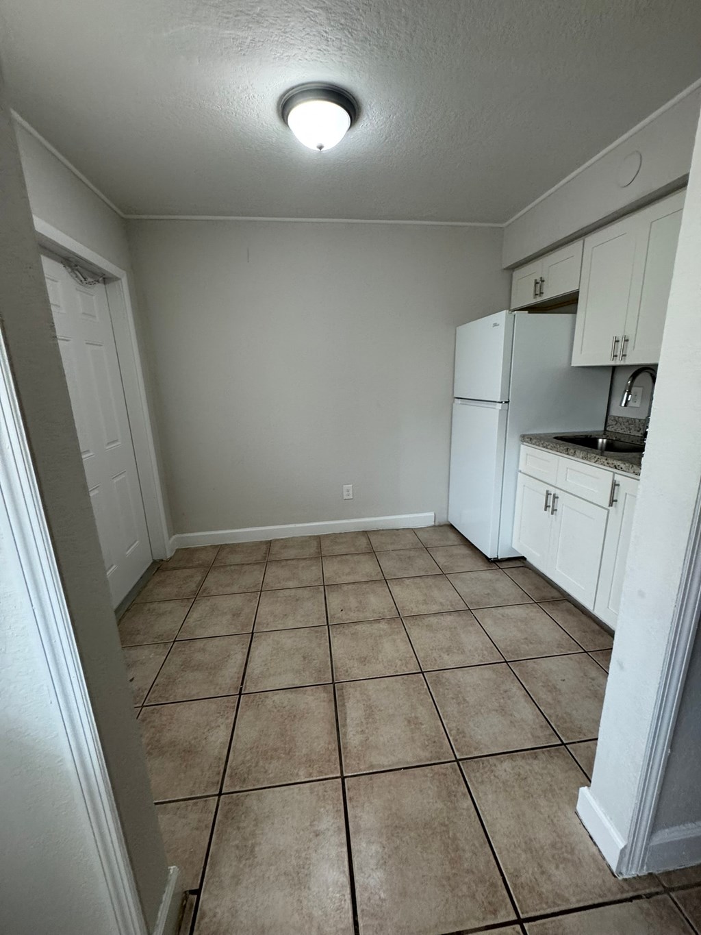 A kitchen with white cabinets and a tiled floor.