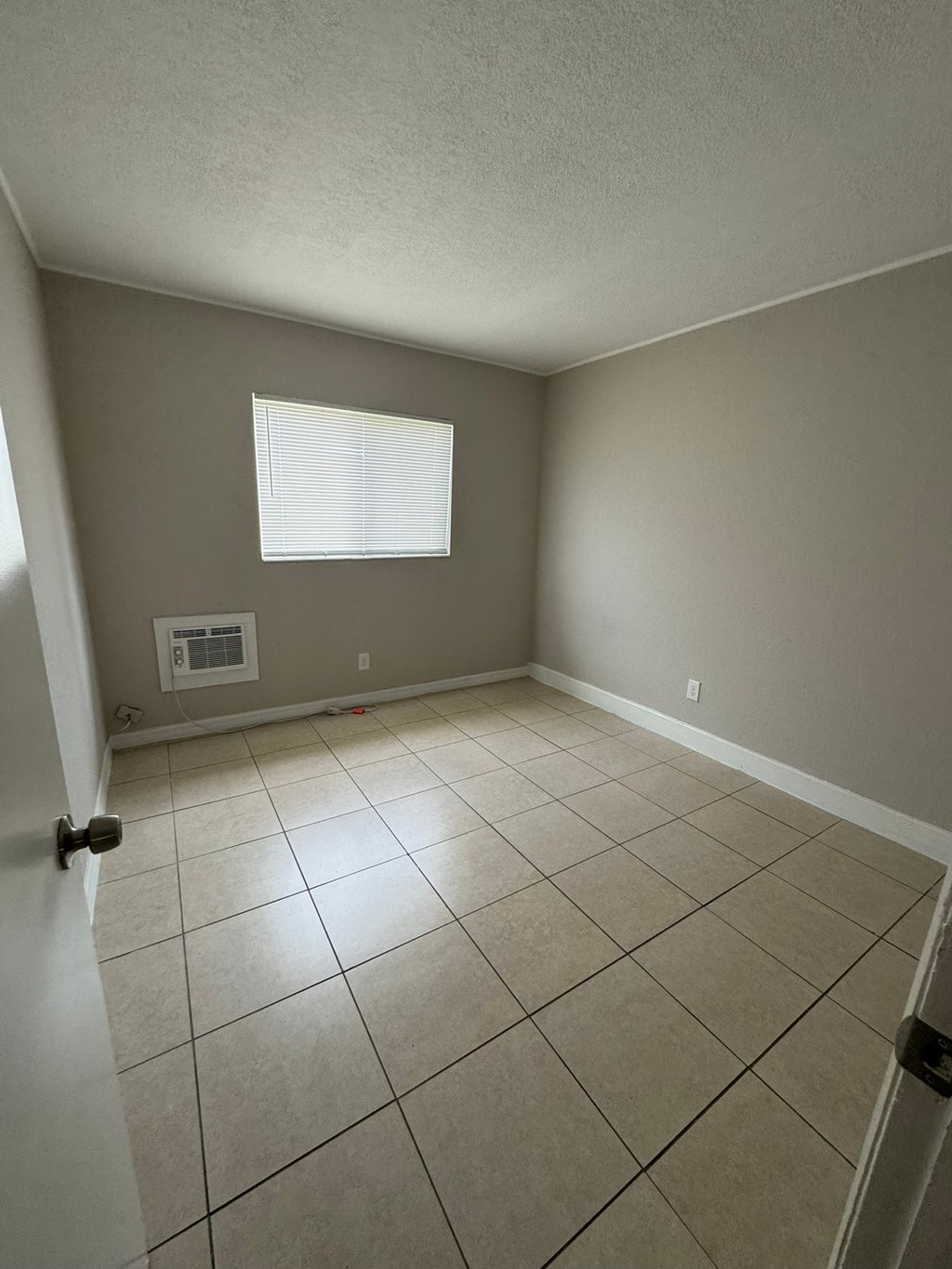 A room with a window and tiled floor.