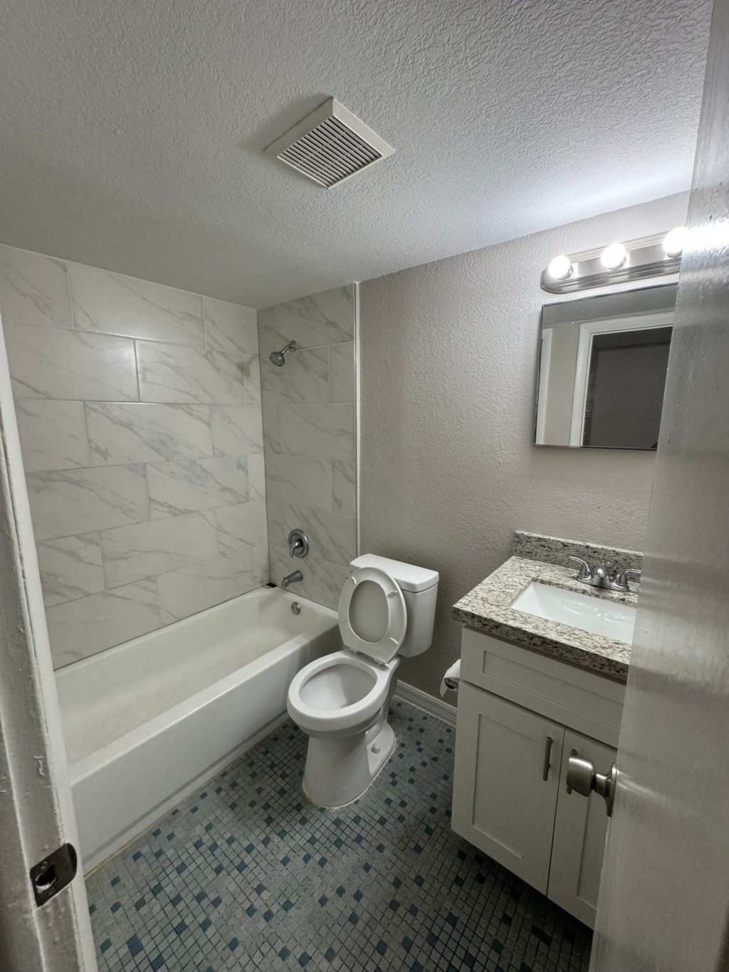A white toilet sits in a bathroom next to a bathtub.