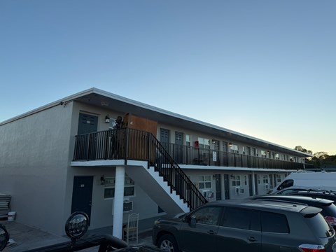 A building with a balcony and a car parked in front.