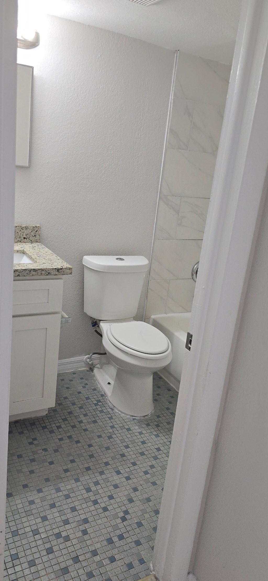 A white toilet in a bathroom with a tiled floor.
