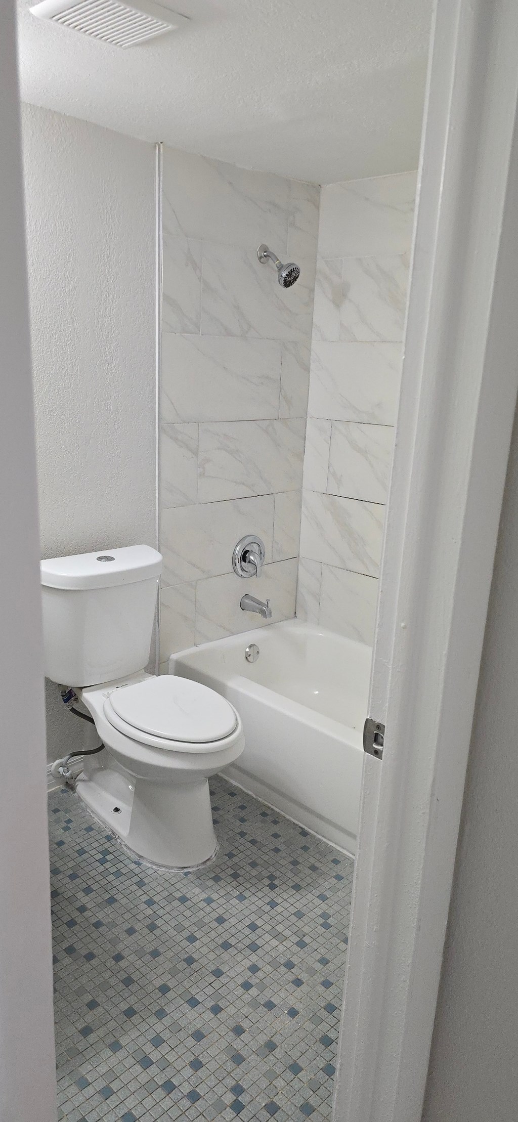 A white toilet in a bathroom with a white tiled shower.