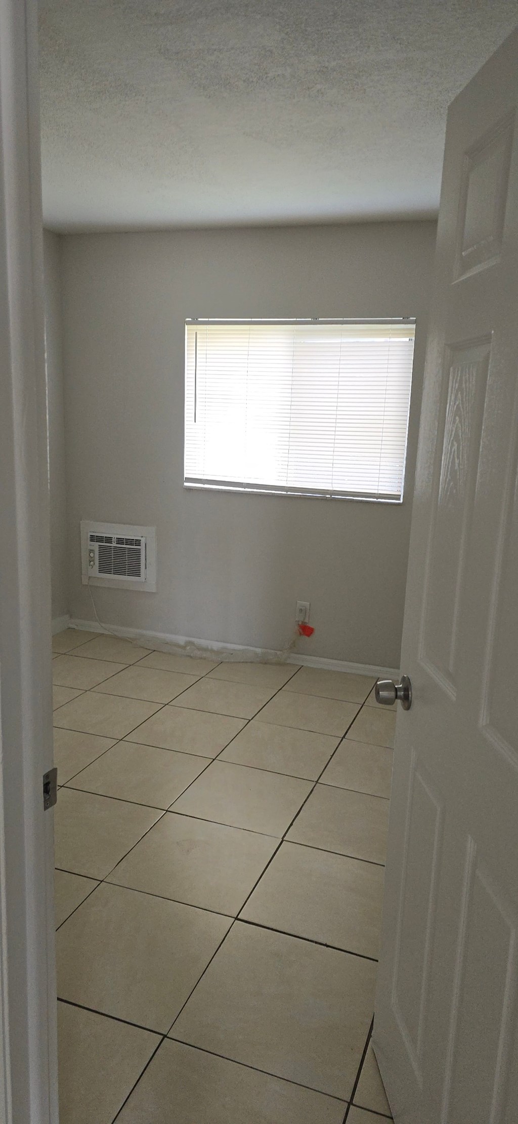 A white door is on the right side of a room with a window.