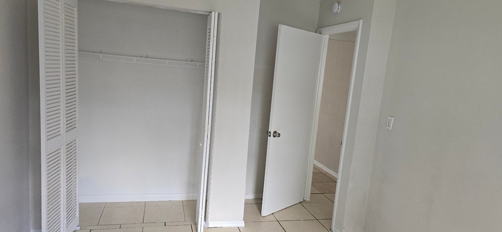 A white door is open to a room with a tiled floor.