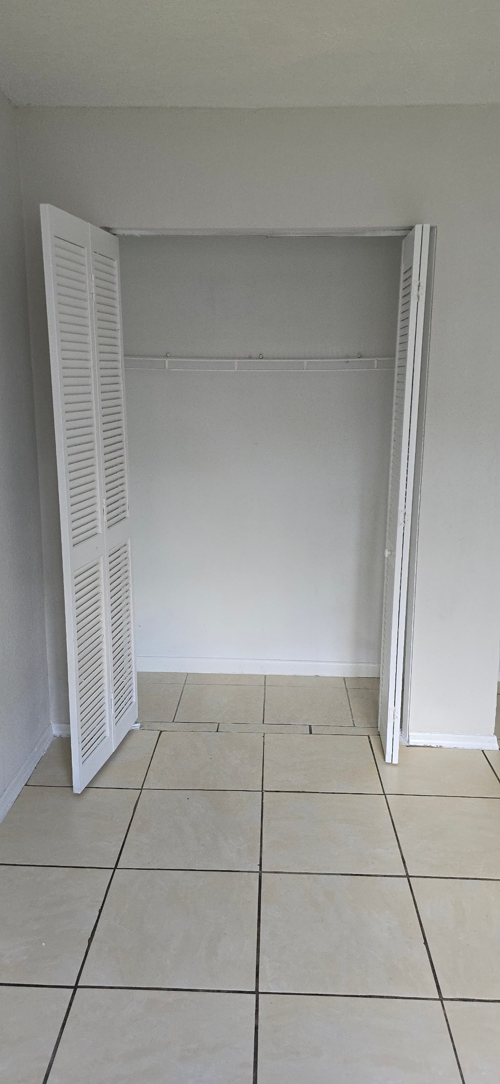 A white closet with a white door and white shelves.