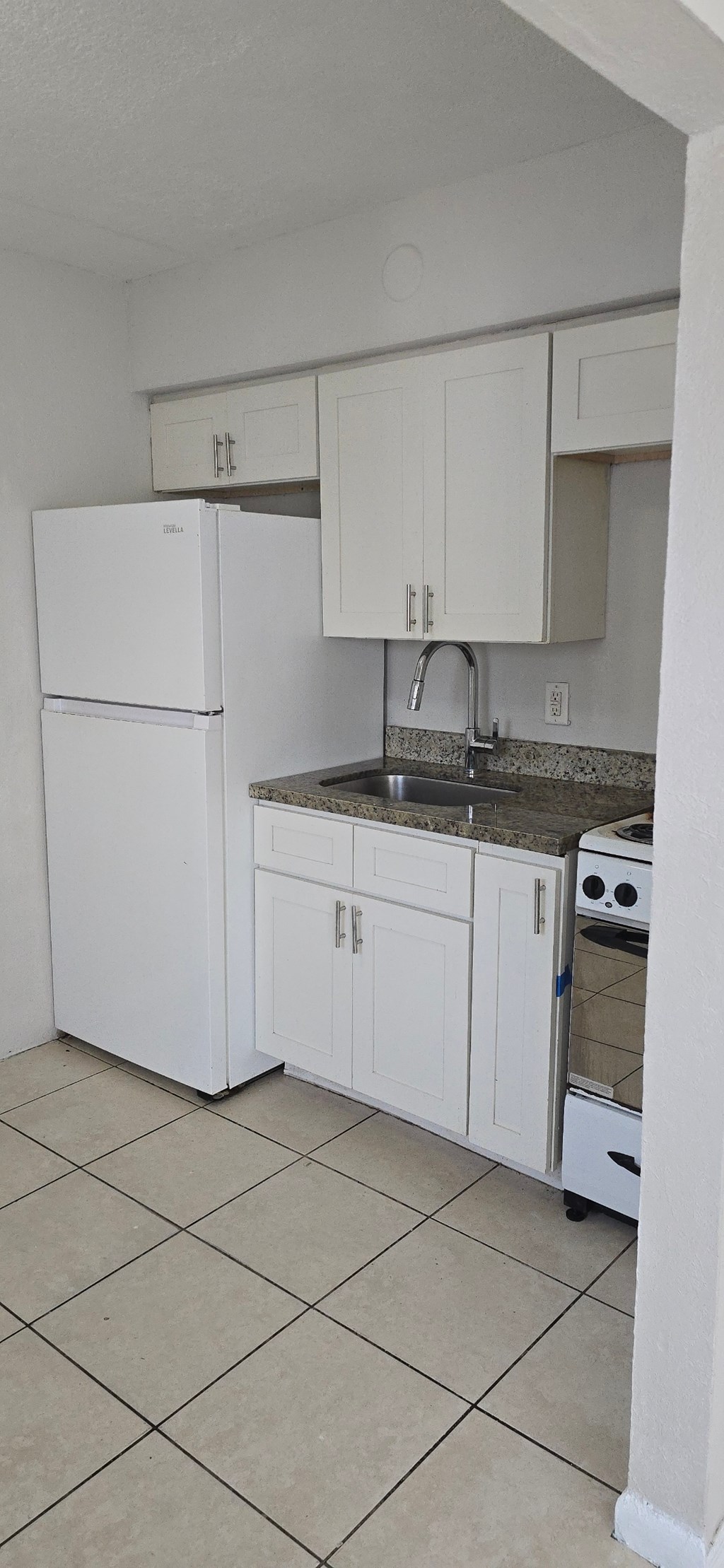 A kitchen with white cabinets and a white refrigerator.