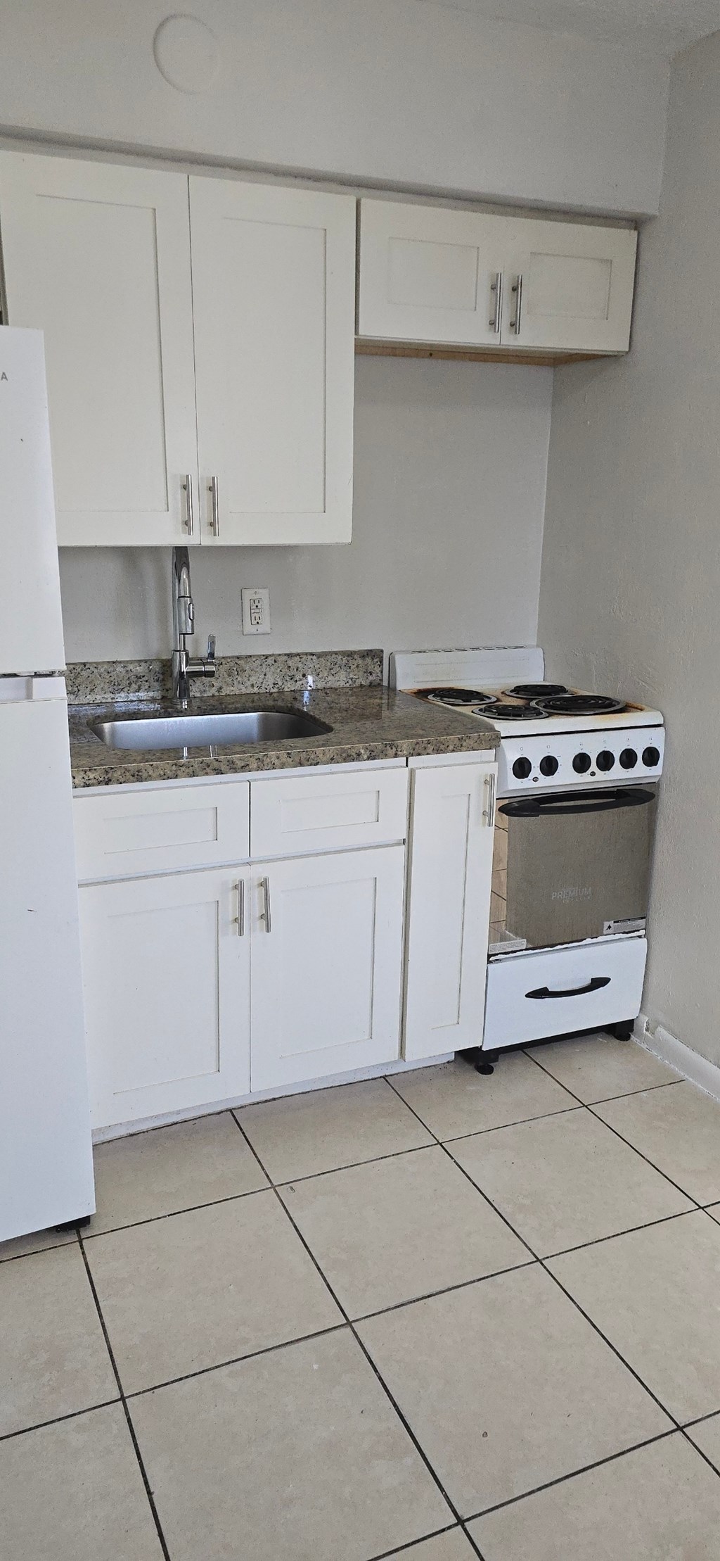 A kitchen with white cabinets and a white fridge.