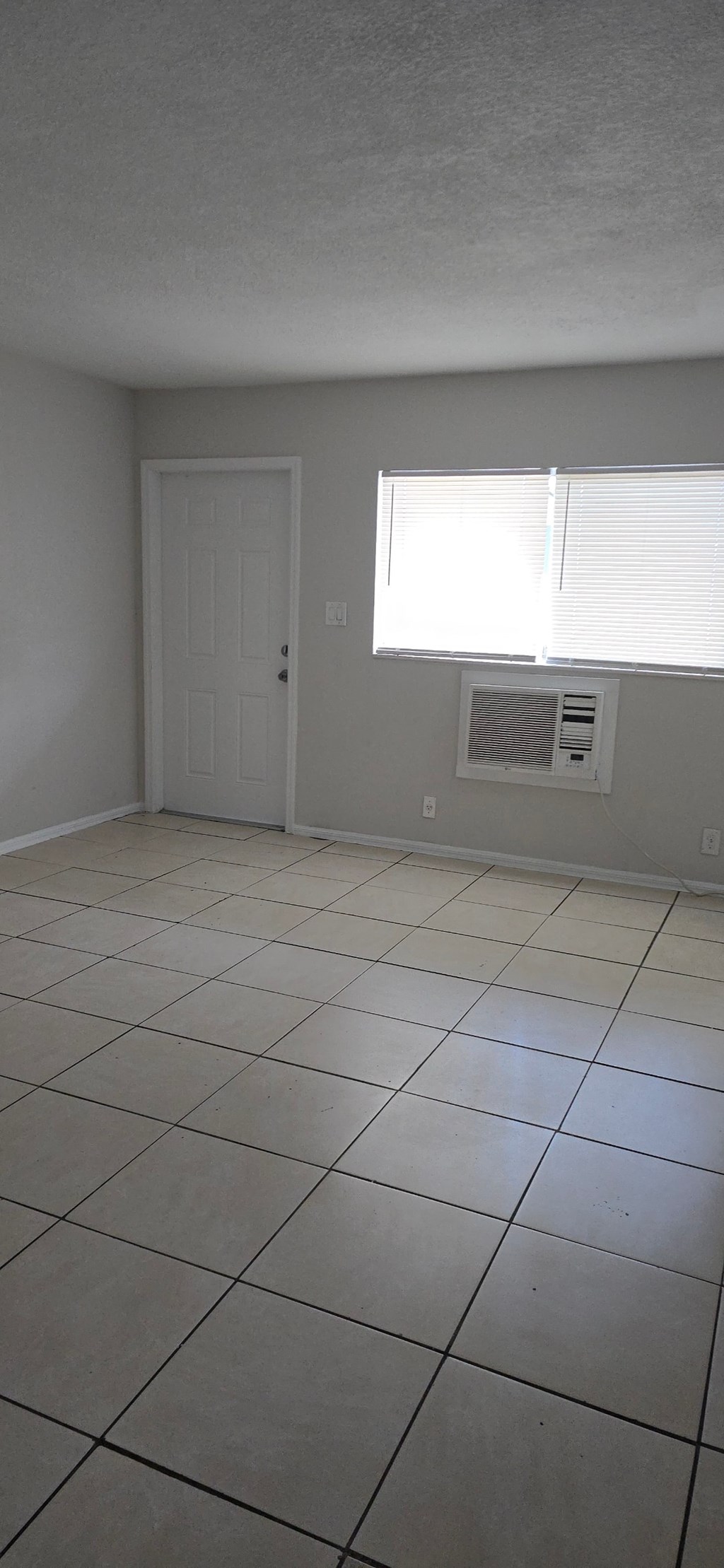 A room with a white door and a window with blinds.